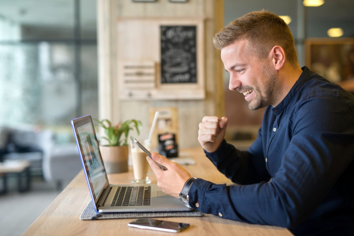 Business owner using phone and laptop at a cafe